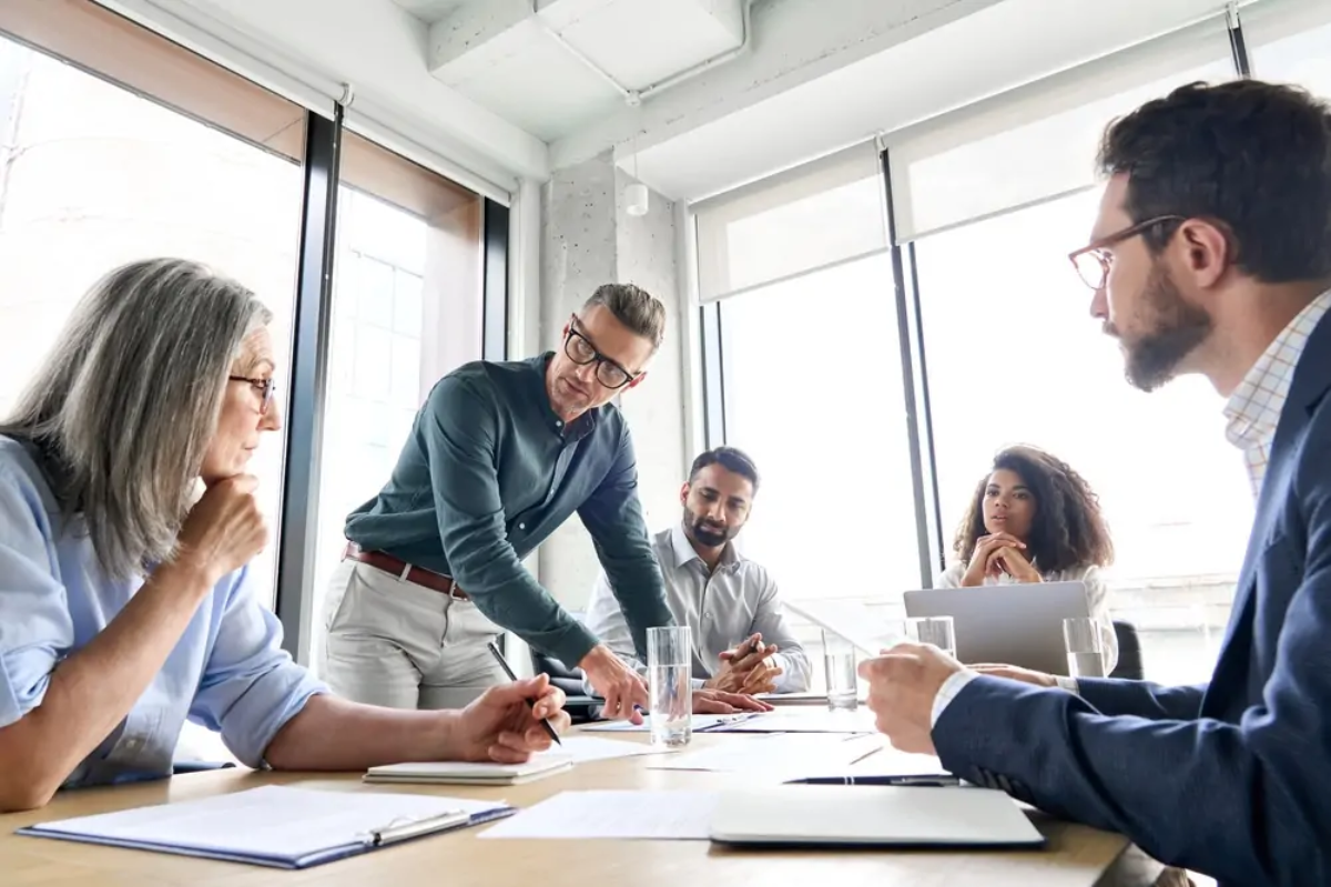 Businessman talking to employees around table in meeting