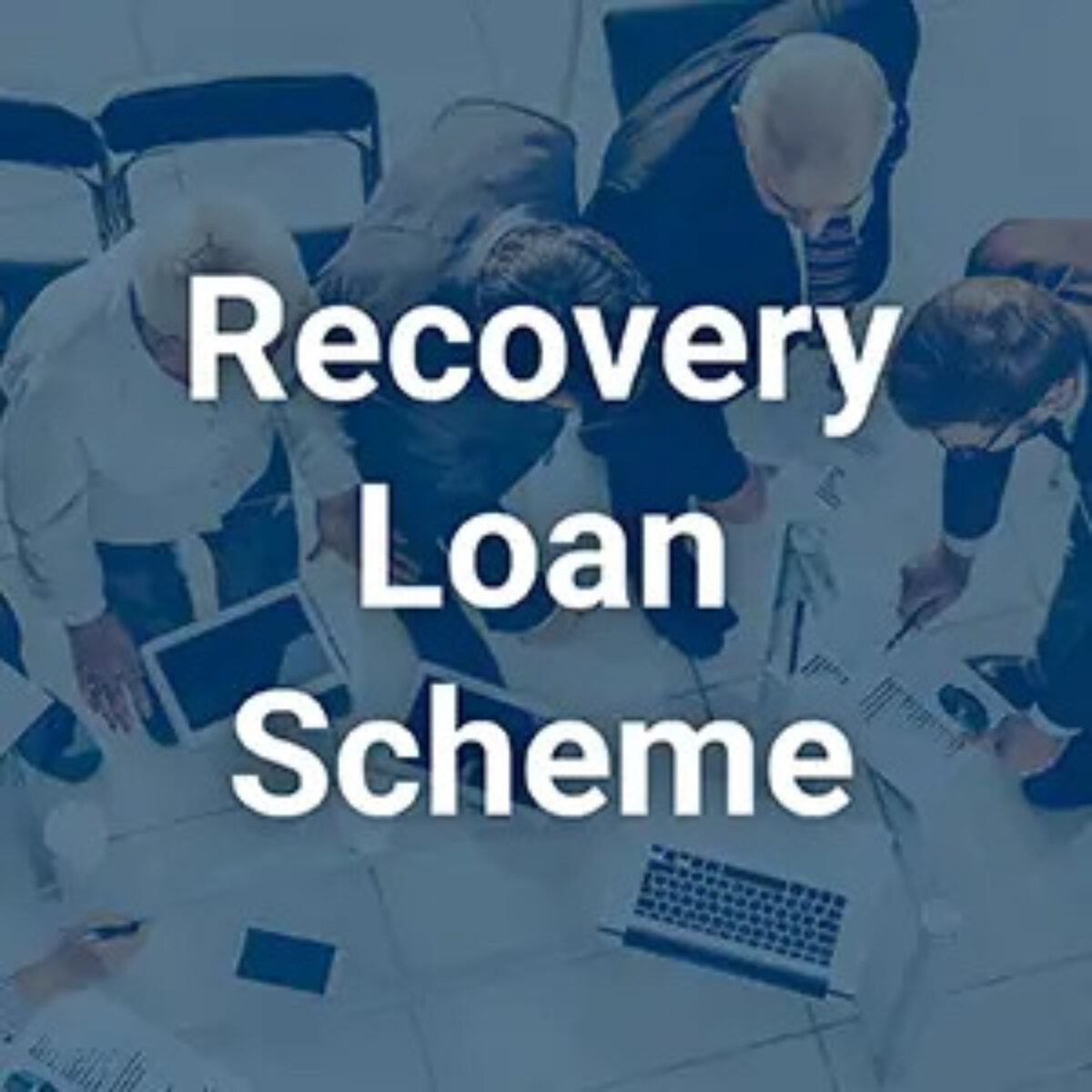 Businessmen standing around table discussing papers in meeting overlayed with text reading 'recovery loan scheme'