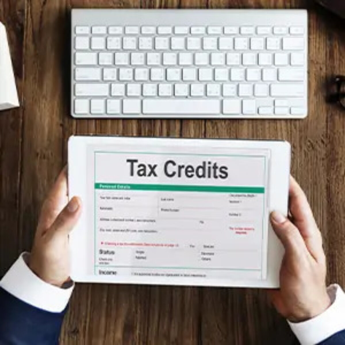 Hands holding a tablet with tax credits page on screen