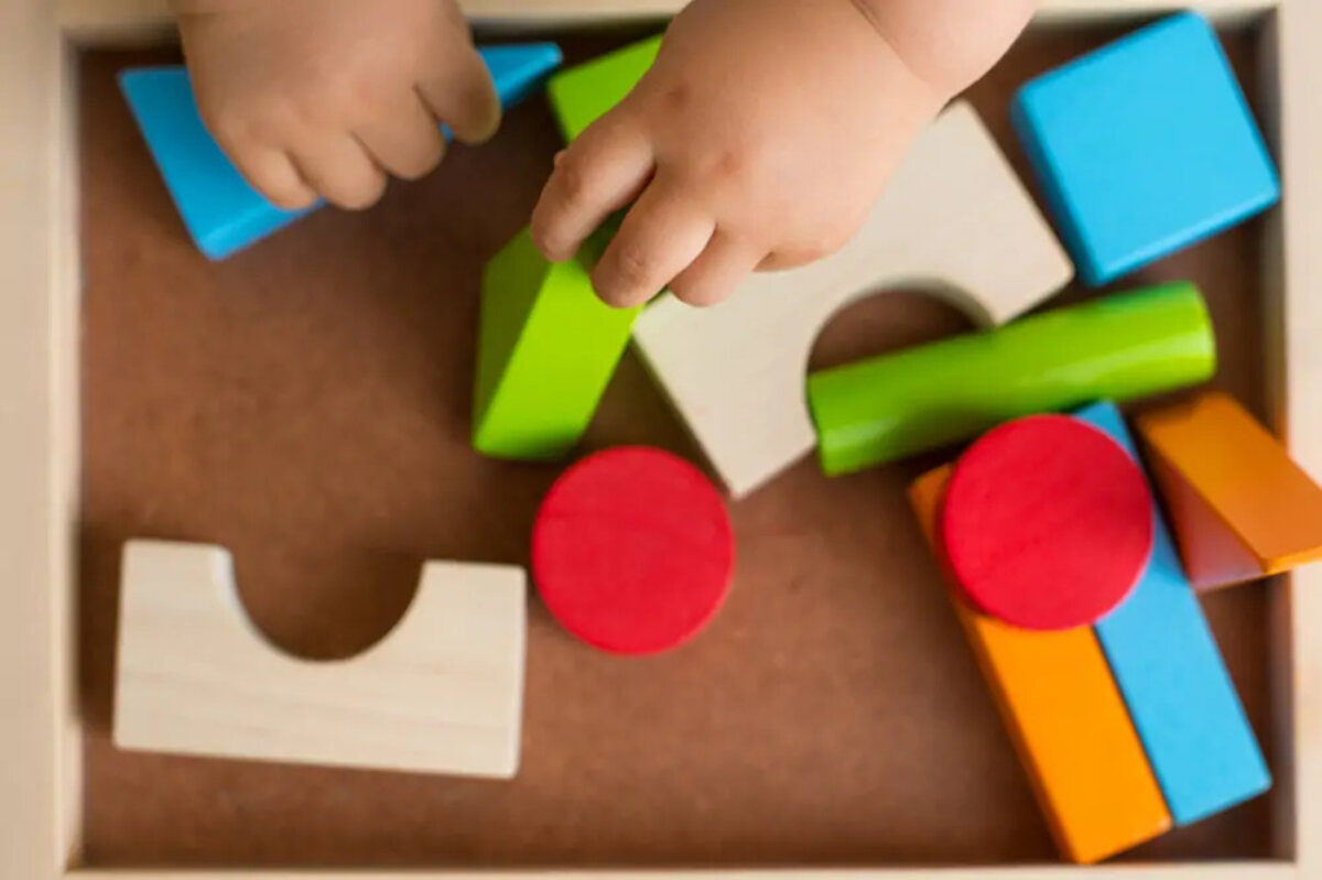 child's hands playing with wooden shaped at childcare facility