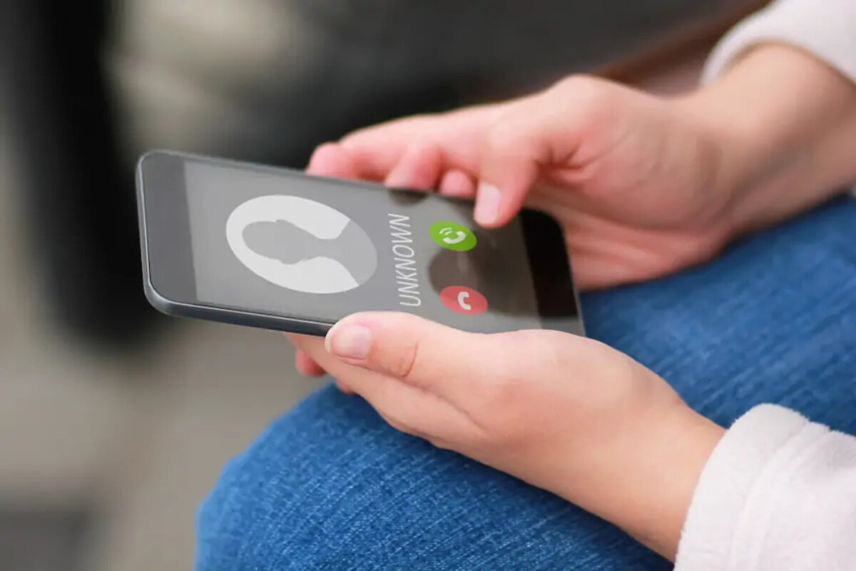 Woman holding smartphone displaying incoming call from unknown number