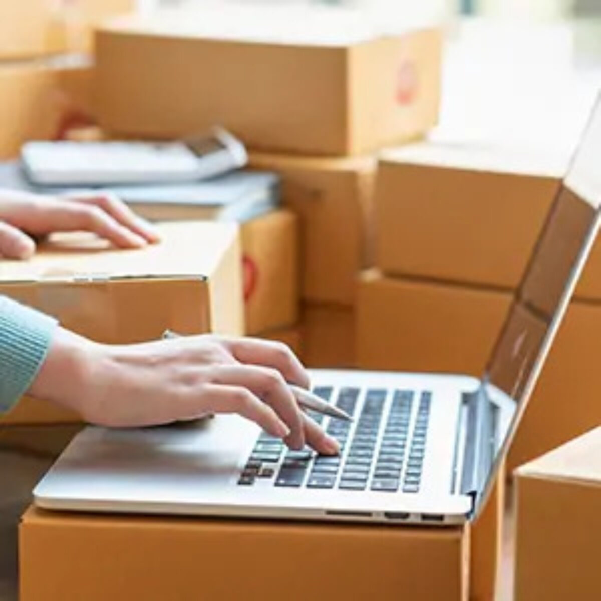 Woman working on laptop surrounded with cardboard boxes