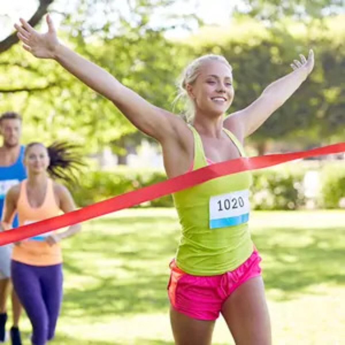 Woman crossing finish line in race and celebrating win