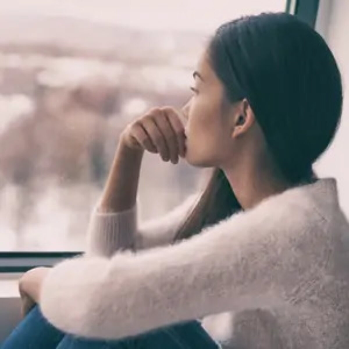 Woman sitting at window staring outside