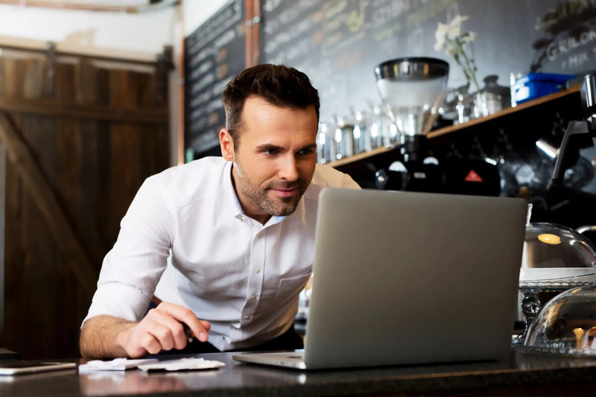 Businessman working on laptop behind coffee shop counter