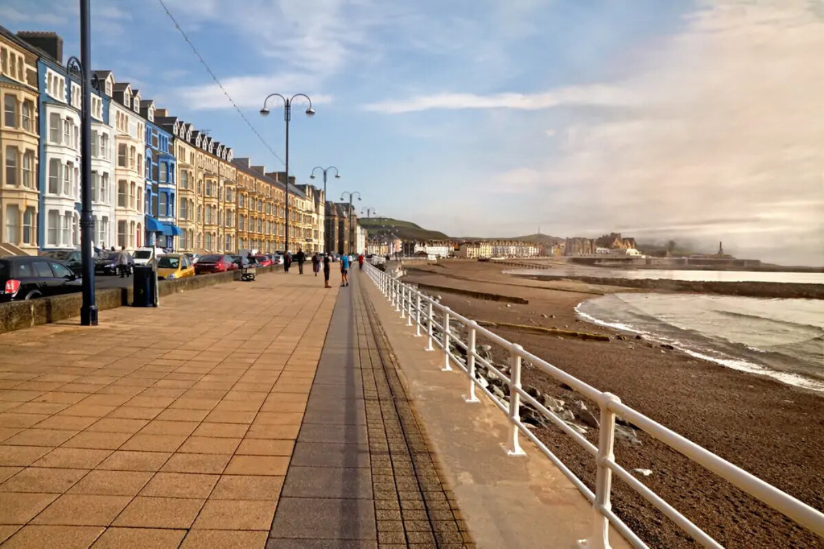 Promenade in Aberystwyth seaside resort with terraced houses on one side and an beach on the other