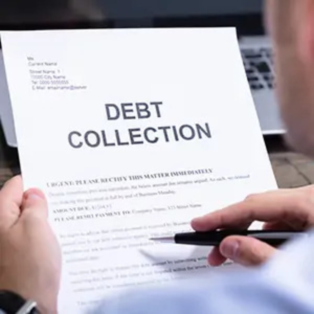 Businessman reading and pointing at debt collection letter with pen