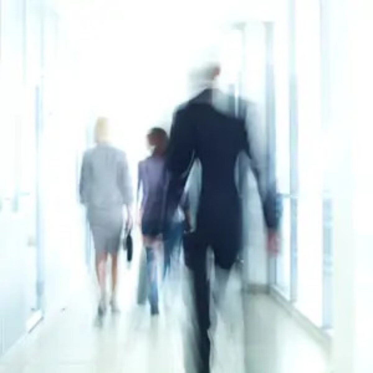 Blurred image of businesspeople walking down office corridor
