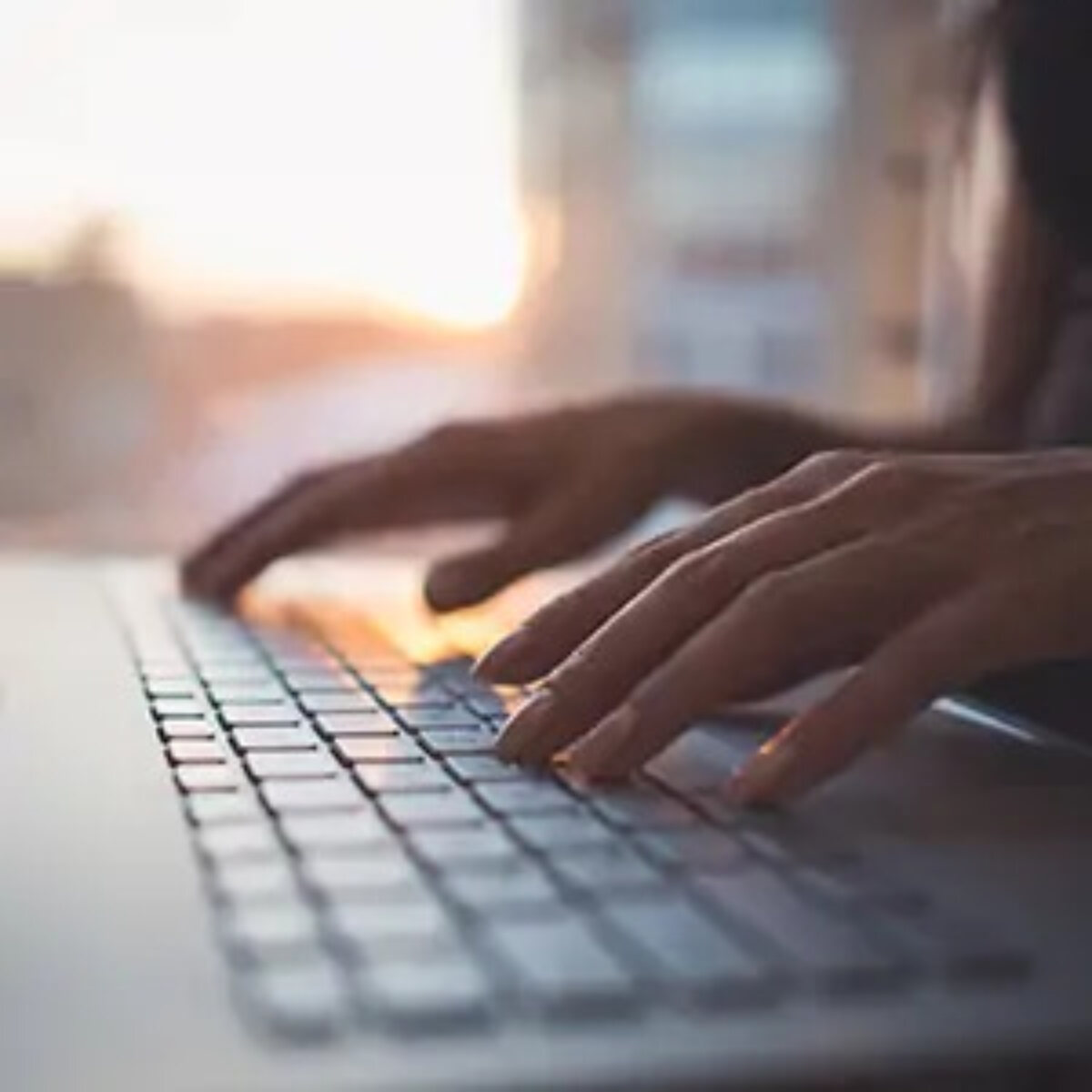 Hands typing on laptop keyboard
