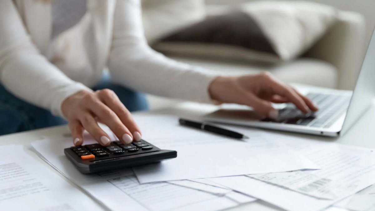 Woman using calculator with one hand and laptop with the other