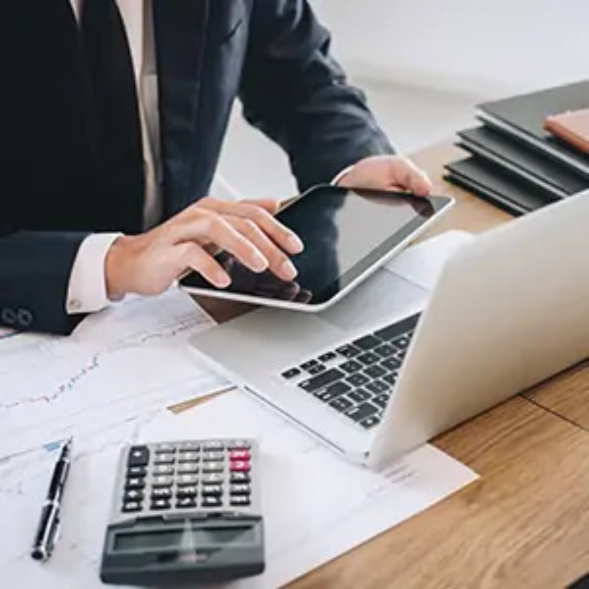 Businessman using tablet in front of laptop and calculator on desk