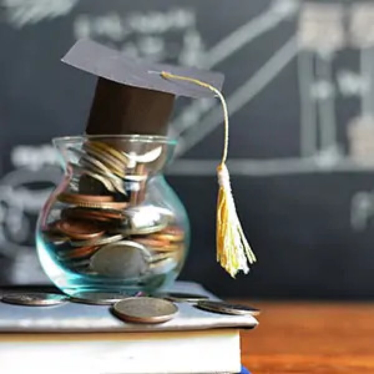 Glass jar filled with coins and a miniature graduation cap on top