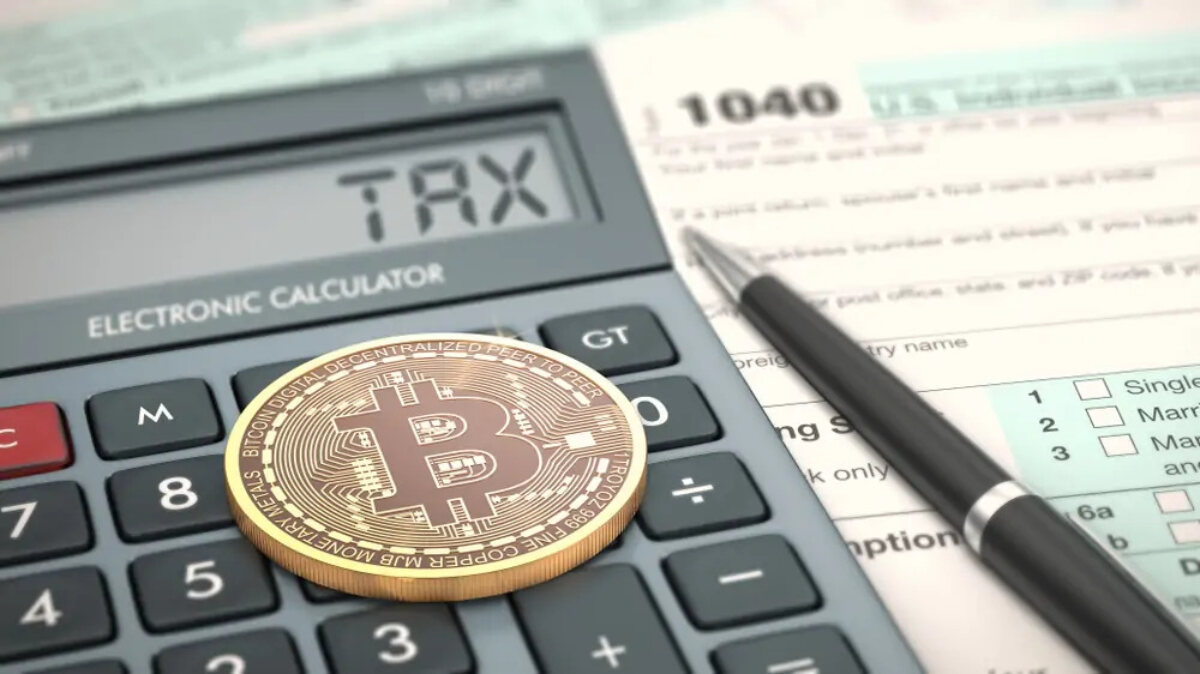 Bitcoin coin on top of a calculator reading 'tax' on screen