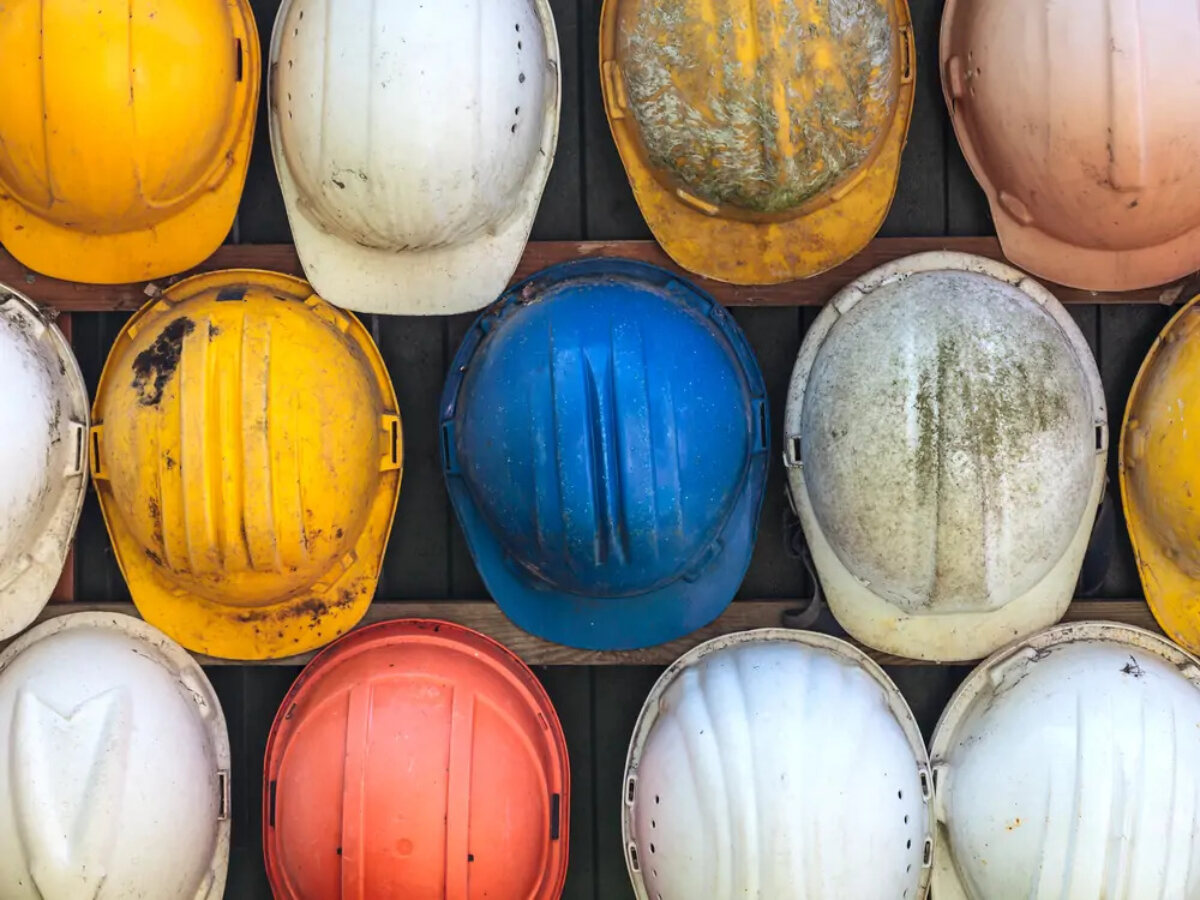 Different-coloured hard hard hanging on wall on construction site