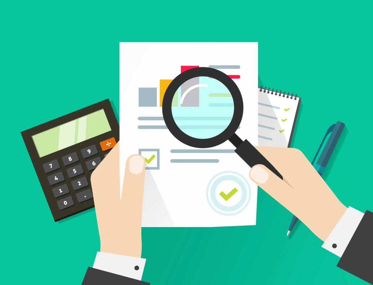 Cartoon of businessman's hands holding a tax document and a magnifying glass over it in front of calculator and notebook and pen