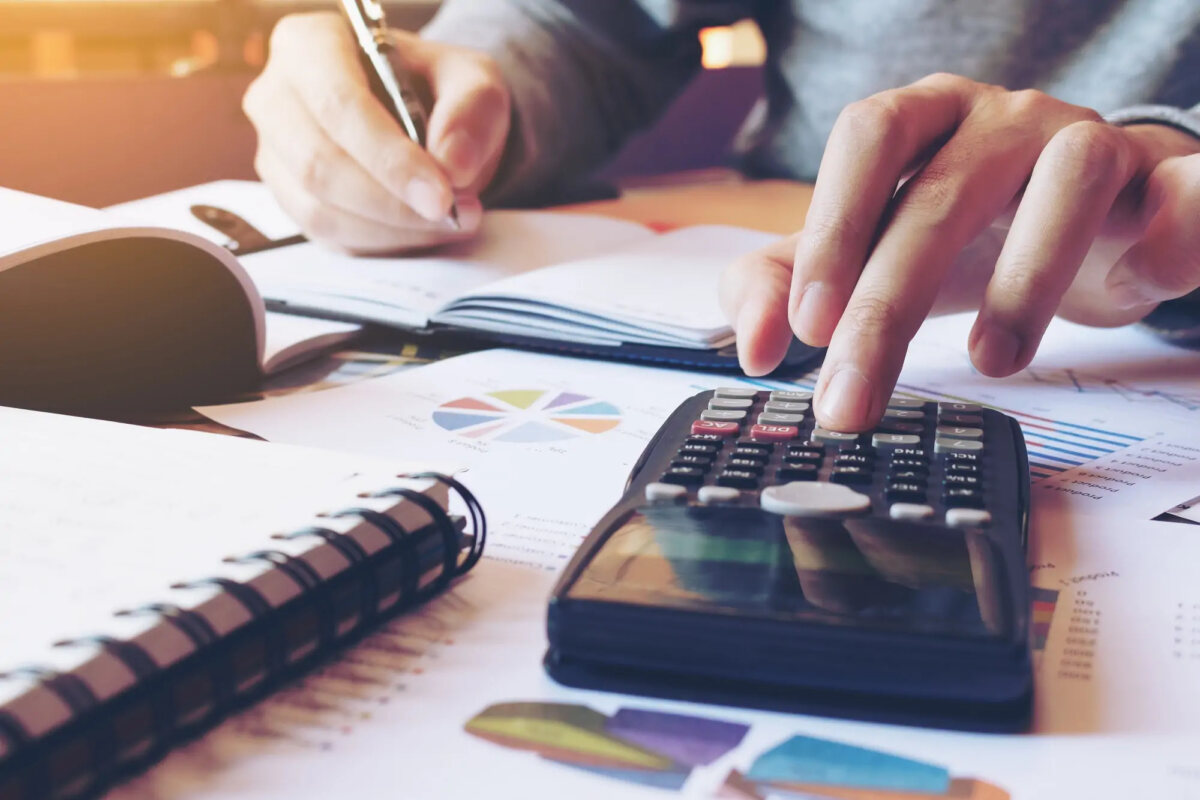 Businessman using calculator with one hand and holding pen in the other