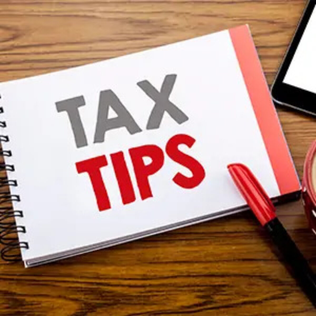 Open notebook on desk with 'tax tips' written on page