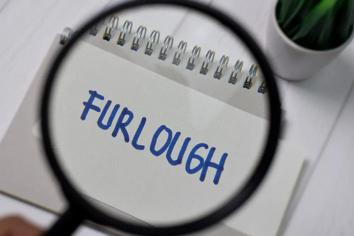 Magnifying glass held over piece of paper with 'furlough' written on it