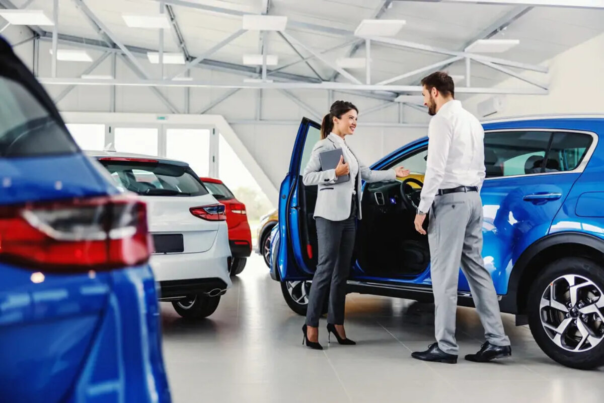 Saleswoman at car dealership showing customer the interior of a vehicle