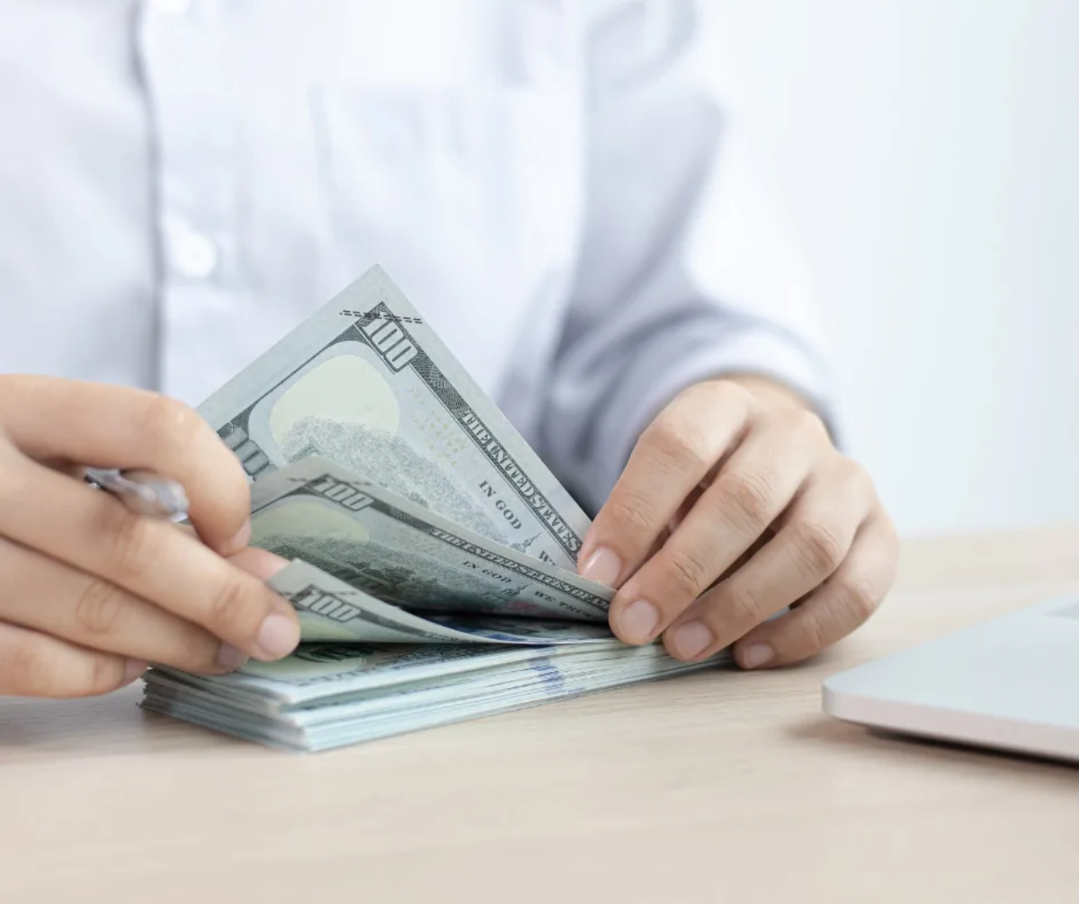 Businessman leafing through wad of cash at desk