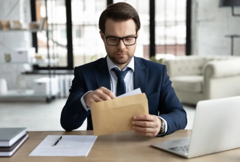 Businessman at desk opening HMRC letter