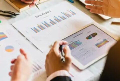 Businesspeople discussing sales report document at desk