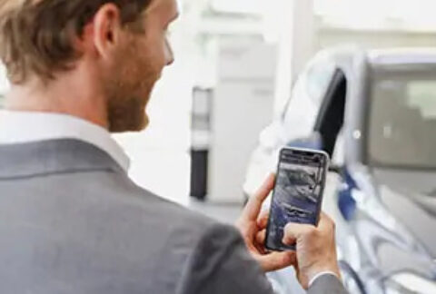 Man using smartphone to take a photo of a car