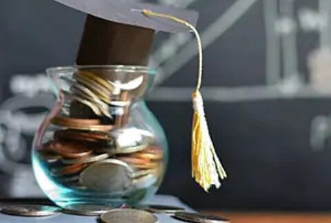 Glass jar filled with coins and a miniature graduation cap on top