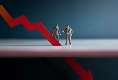 Businessmen figurines standing behind a downwards arrow that extends below surface they are standing on