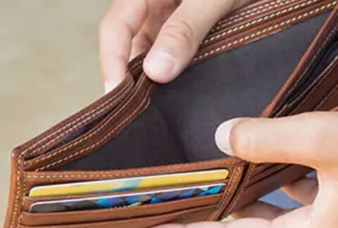 Man holding open wallet with no cash inside and two cards in slots