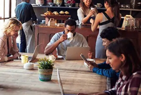 Group of businesspeople working independently at one table in coffee shop