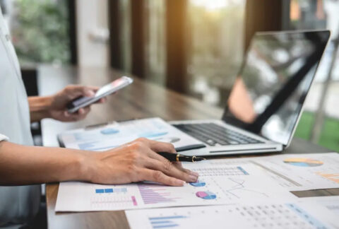 Businesswoman holding phone in one hand and a pen over a document in the other