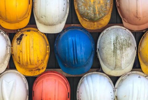 Different-coloured hard hard hanging on wall on construction site