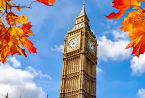 Big ben against a blue sky and clouds with autumnal orange leaves in foreground