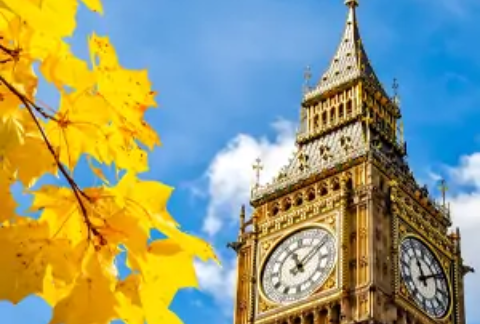 Big ben against a blue sky and clouds with autumnal yellow leaves in foreground