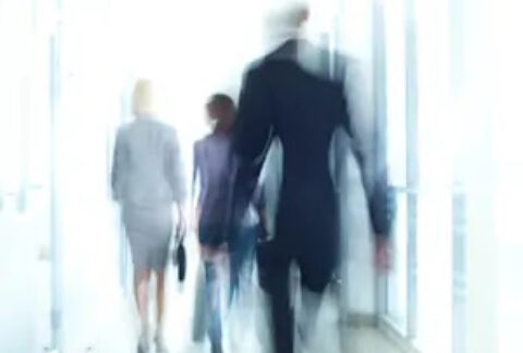 Blurred image of businesspeople walking down office corridor