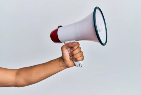 Outstretched arm with hand holding megaphone