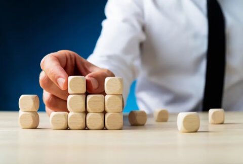 Businessman stacking wooden dice-shaped cubes to look like a bar chart