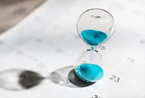 Sand timer in progress sitting on top of calendar page