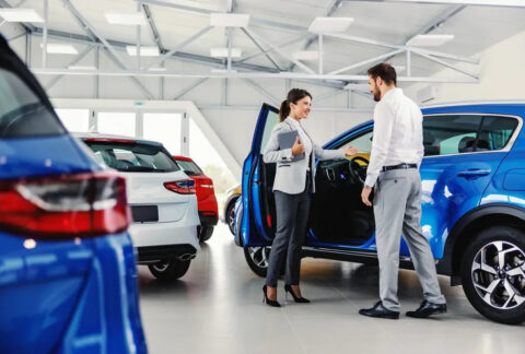 Saleswoman at car dealership showing customer the interior of a vehicle