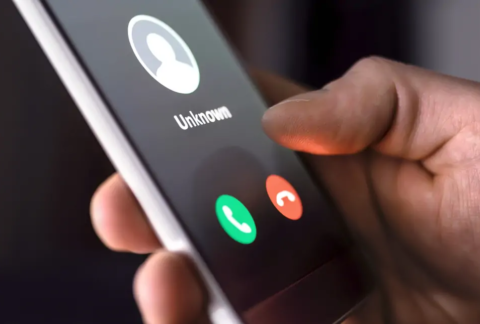 Hand holding smartphone displaying incoming call from unknown number