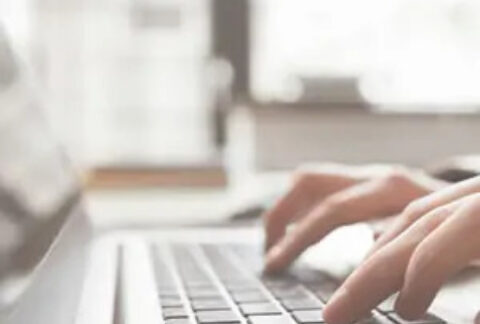 Hands typing on a laptop keyboard
