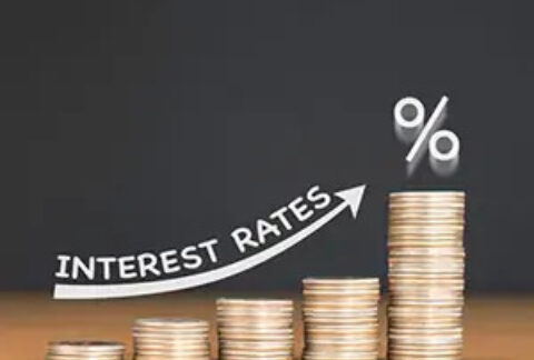 Five stacks of coins increasing in height with an image of an upward arrow with the words 'interest rates' above it and a percentage symbol above the tallest stack