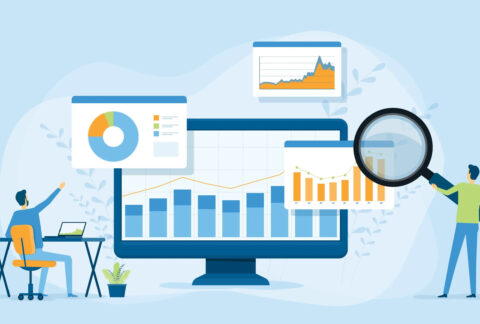 Cartoon of two miniature businessmen, one sitting at desk and one standing holding magnifying glass looking at computer screen and floating graphs and charts