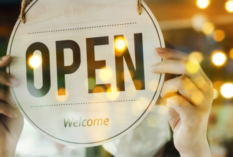 Small business owner turning over 'open' sign through window