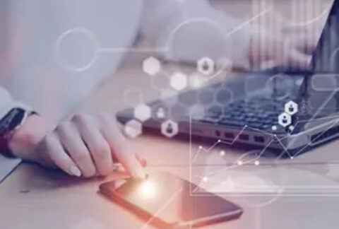 Businessperson using smartphone and laptop overlayed with technology graphics