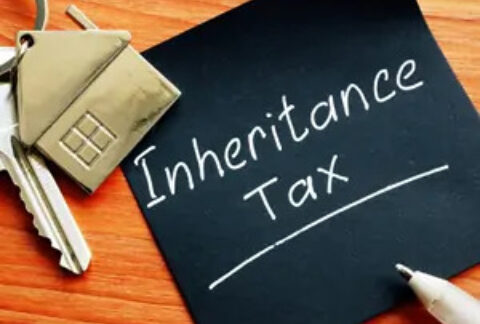 Post-it note with 'inheritance tax' written on it next to a key with a house keyring