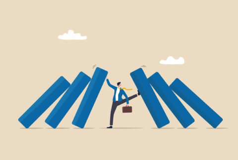 Cartoon of miniature businessman with books falling inwards on either side, holding them up with his hand on one side and his foot on the other