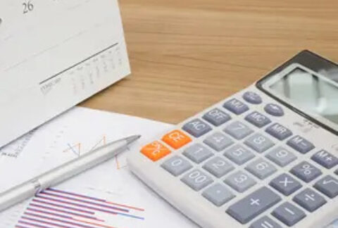 Calculator, pen and calendar on top of graph sheets