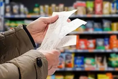 Shopper standing in aisle holding receipts